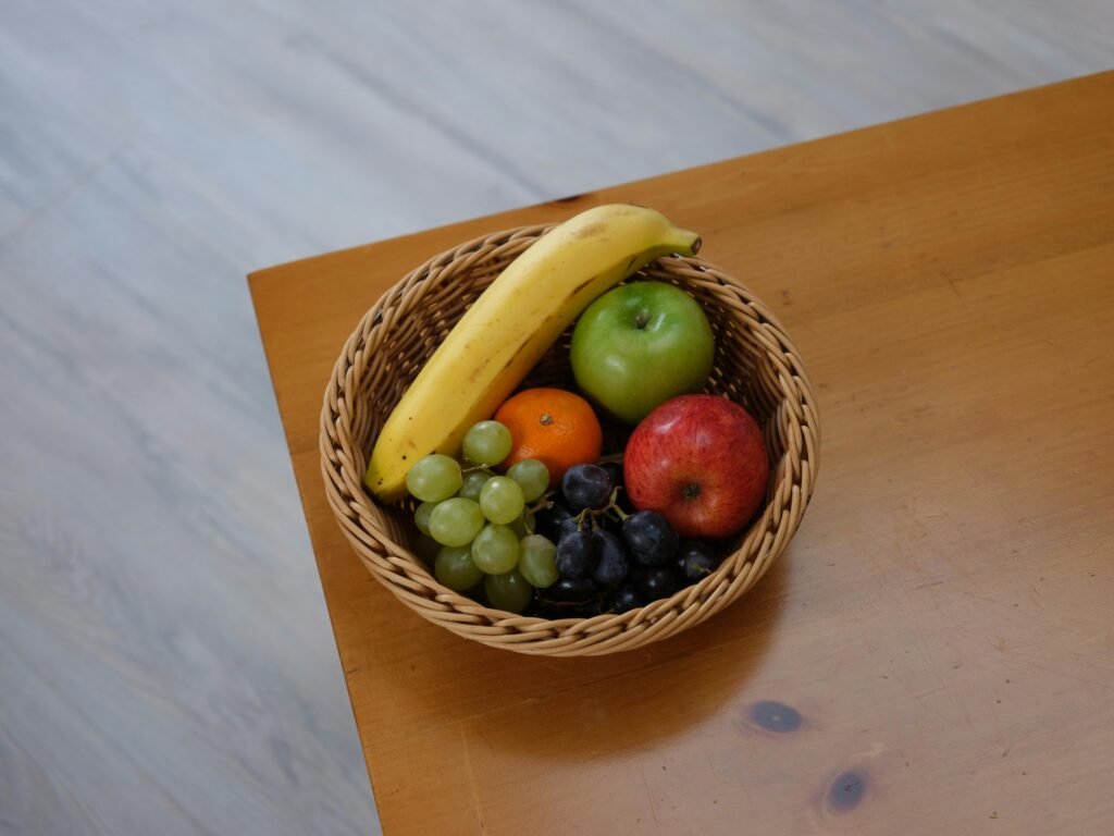 Vibrant assortment of fruits in a woven basket on a wooden tabletop.