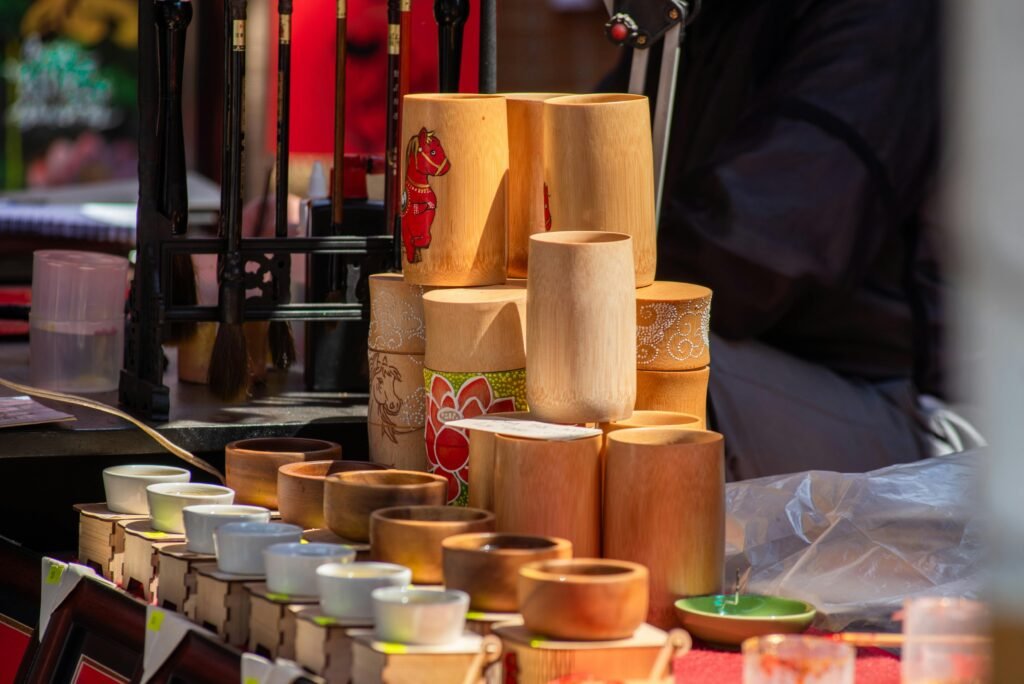 Our Products A close-up of a stack of wooden cups displayed at an outdoor market stall, showcasing handcrafted artistry.