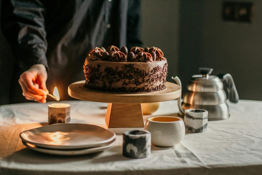 Crop anonymous person lightning candle with burning match while serving table for dessert with sweet cake